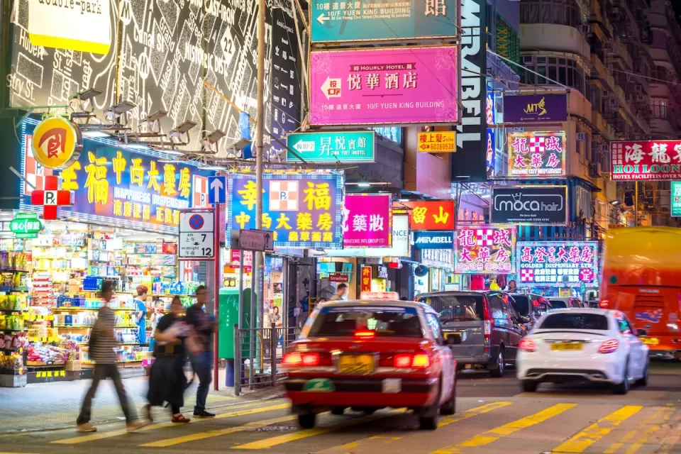 Cars and pedestrians on Hong Kong street at night.